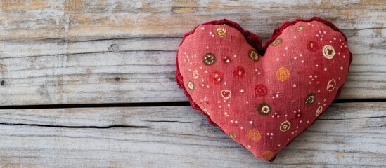 Fototapeta premium Red fabric heart decoration on rustic wooden table representing love and affection for Valentine's Day celebrations and romantic occasions
