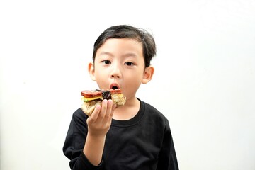 A cheerful boy in a black shirt smiles while holding a delicious spam musubi. The minimalistic...