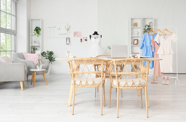 Interior of wedding planner's office with table, clothes and armchairs