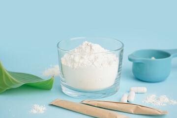 Bowl and scoop with collagen powder on blue background