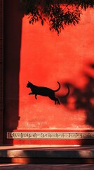 Silhouette of a cat against a vibrant red wall, highlighted by sunlight and tree shadows, creating a striking visual contrast.