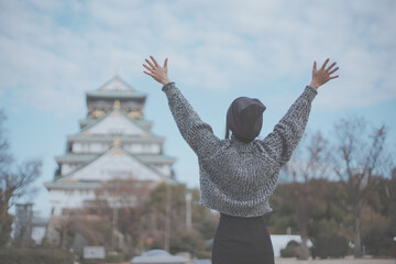 Fototapeta premium 大阪城と喜ぶ女性旅行者の後ろ姿