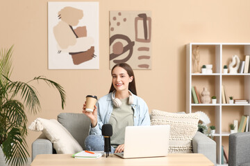 Young woman with coffee cup recording podcast at home