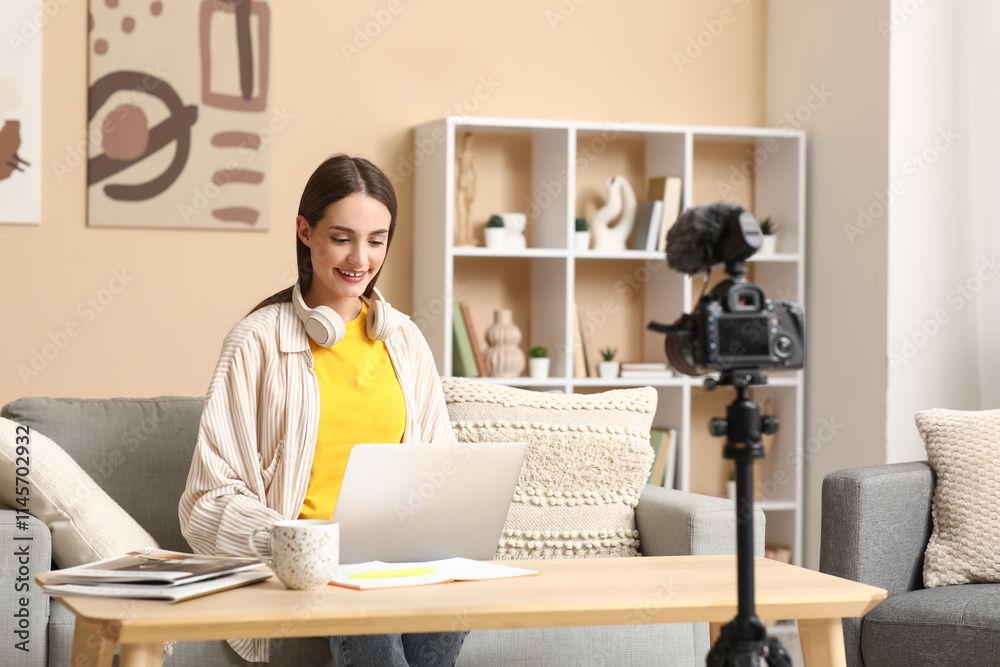 Wall mural Young woman with laptop on table recording podcast at home