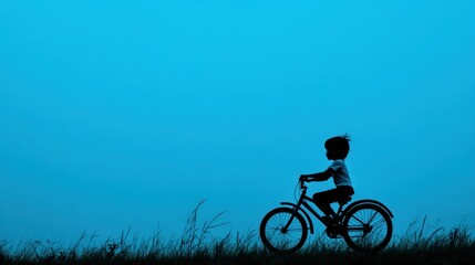Obraz premium Child's silhouette riding bicycle at dusk.