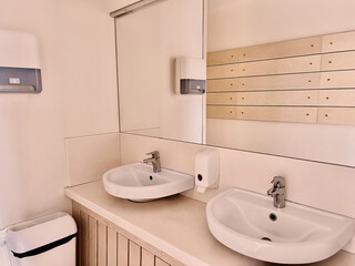 single sink in small public toilet with wall soap dispenser and paper towlels