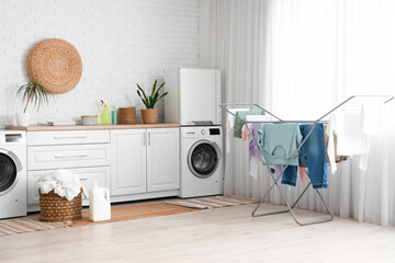 Modern laundry room interior with washing machine, dryer and wicker basket