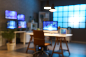 Blurred view of dark office with trader's desks and glowing lamps at night