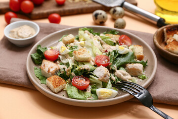 Plate with tasty chicken Caesar salad and bowl of sauce on orange background, closeup
