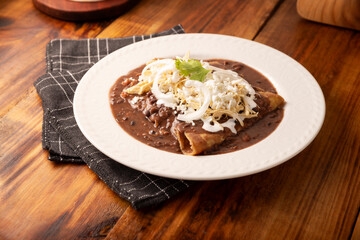 Enfrijoladas. Corn tortillas dipped in bean sauce, covered with cream and cheese, they can be covered or filled with chicken meat, cheese or some other ingredient. Traditional Mexican dish.