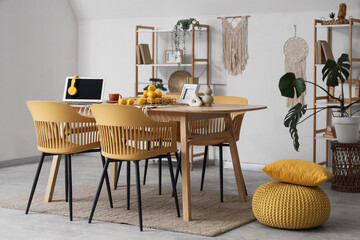 Interior of modern dining room with laptop and fresh lemons on table