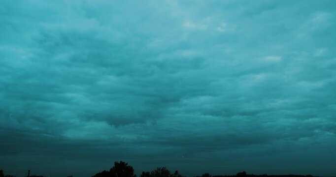 Timelapse of dark blue overcast sky with fast moving storm clouds  and many airplanes visible as shining fast moving lights consecutively flying above the horizon as they descend for landing