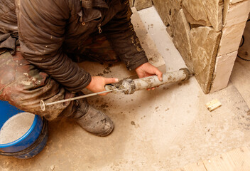 A man is working on a project, using a caulking gun to fill a crack in a wall