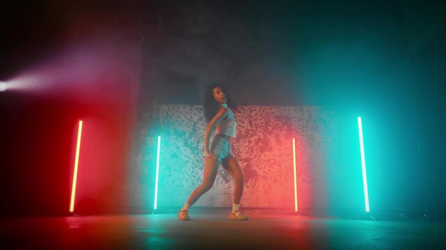 Hip-hop, breakdance and reggaeton dance style, beautiful African woman dancing. Talented mixed race lady rehearsing and performing trendy contemporary dance movements, slow motion, female silhouette