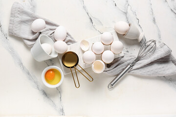 Holder and bowl with raw chicken eggs on white background