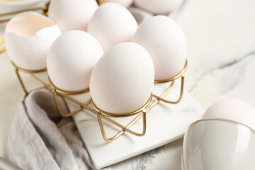 Holder with raw chicken eggs on white background