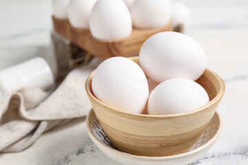 Bowl with raw chicken eggs on white background