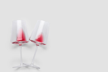 Glasses with leftover red wine on white background