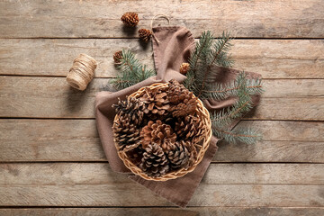 Wicker bowl with pine cones and fir branches on wooden background
