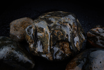 Several rounded natural stones on a black background. Beautiful texture of natural stone. Pebbles, cobblestones.
