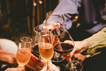 A group of friends enjoy an outdoor evening, drinking wine in a friendly and lively atmosphere. They celebrate togetherness, happiness and bonding.