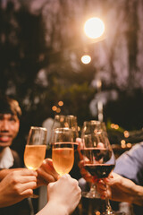 A group of friends enjoy an outdoor evening, drinking wine in a friendly and lively atmosphere. They celebrate togetherness, happiness and bonding.