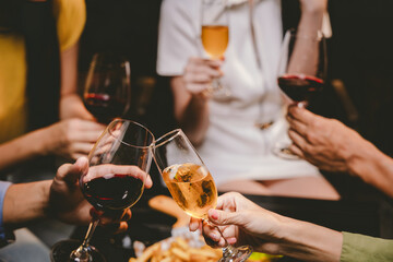 A group of friends enjoy an outdoor evening, drinking wine in a friendly and lively atmosphere. They celebrate togetherness, happiness and bonding.