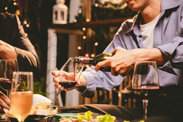 A cheerful group of friends enjoying wine and food on a sunny patio. Toasting with wineglasses, they celebrate togetherness in a scenic outdoor setting, blending fun, friendship, and a festive mood.