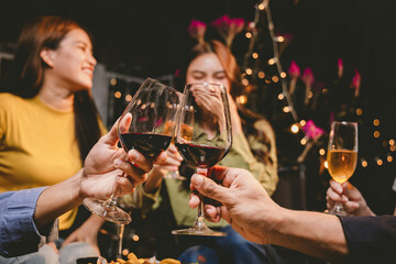 A joyful group of friends and family gathered around a dinner table, raising wine glasses in a celebratory toast. Smiling and laughing, they enjoy food, drinks, and togetherness in a festive atmospher