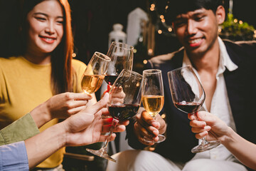 A joyful group of friends and family gathered around a dinner table, raising wine glasses in a celebratory toast. Smiling and laughing, they enjoy food, drinks, and togetherness in a festive atmospher