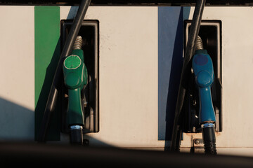 Close of of blue and green fuel nozzles in petrol station