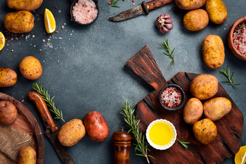 Background Cooking dishes from potatoes. Fresh potatoes, kitchen cutting board, knife and spices. On a wooden background. Free space for text.