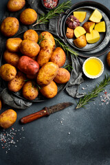 Raw organic potatoes, rosemary, oil and spices. Cooking background. On a gray stone kitchen table.