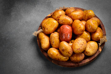 Wooden tray with raw organic potatoes. Side view, close-up.