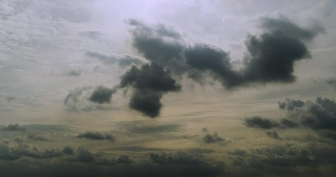 Timelapse of a cloudscape with fluffy cumulus clouds moving and rolling fast across the overcast sky with visible rays of sunlight creating a dreamy atmosphere before the clouds get darker in the end 