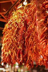 Vibrant, dried red chili peppers hang in dense clusters, their rich, fiery hues catching the light, perfect for culinary uses to add heat and flavor.