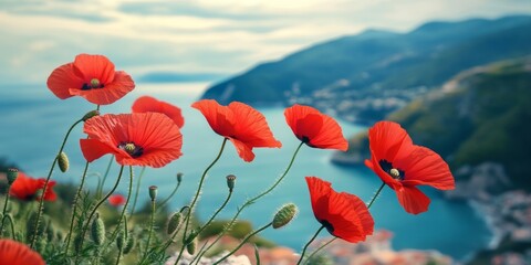 Obraz premium Vibrant blooming red poppies adorn a mountain slope by the sea, showcasing beautiful spring flowers in a stunning display. This red floral design captivates with its selective blurred soft focus.