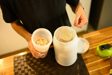 Close up unrecognizable woman preparing protein shake before training in warm kitchen