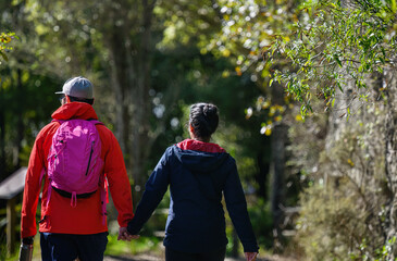 Couple holding hands and walking in the bush in winter.