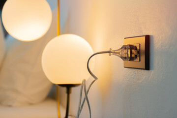 Illuminated electric lamp and electric socket in bedroom. Bright light illuminates hotel room
