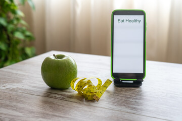 "Eat Healthy" Message On Smartphone With Green Apple And Measuring Tape Highlighting Fitness, Nutrition, And Weight Management.
