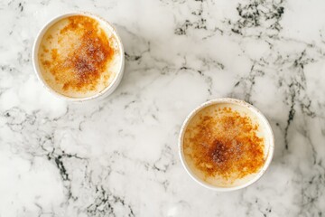 The photo depicts two bowls of rice pudding sprinkled with cinnamon, elegantly placed on a sophisticated marble surface, illustrating a taste of simplicity and warmth.