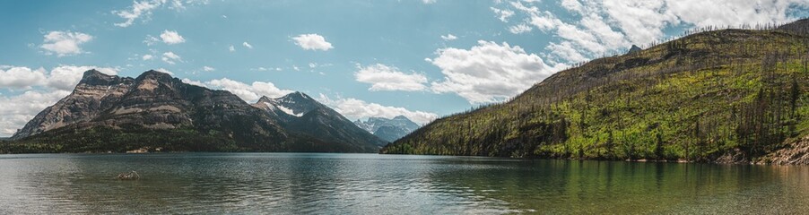 Panoramic lake and mountain view under blue sky.