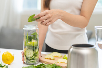 Vegetable smoothie detox, woman hand making healthy raw fresh green fruit juice with blender machine, preparing drink with spinach in kitchen at home, eating vegan diet. Healthy dieting, weight loss.