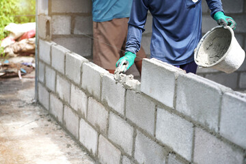 masonry worker make concrete wall by cement block and plaster at construction site
