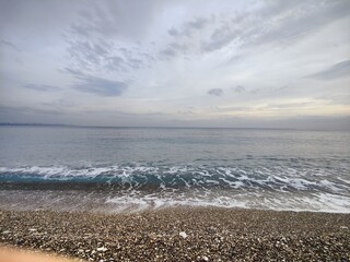 The Silent Shore: A Metaphor of Endless Horizons and Fleeting Waves, Where Pebbled Stillness Meets the Moody Sky, Reflecting a Timeless Serenity Amid the Calm Before the Storm in Nature’s Unspoken.