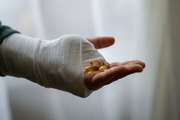 Close-up of a hand in a plaster cast, holding a bunch of soft-shell capsules