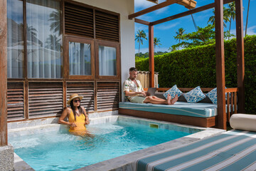 Freelancer enjoys tropical vibes while working remotely by the pool in Thailand