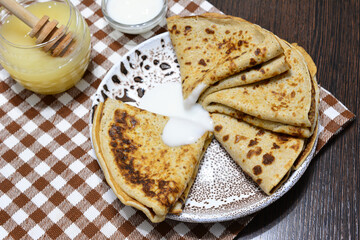 a plate of pancakes with sour cream and a jar of honey   