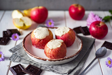 Baked apples with cottage cheese and raisins on a white plate on a white table. A sweet breakfast. Close-up